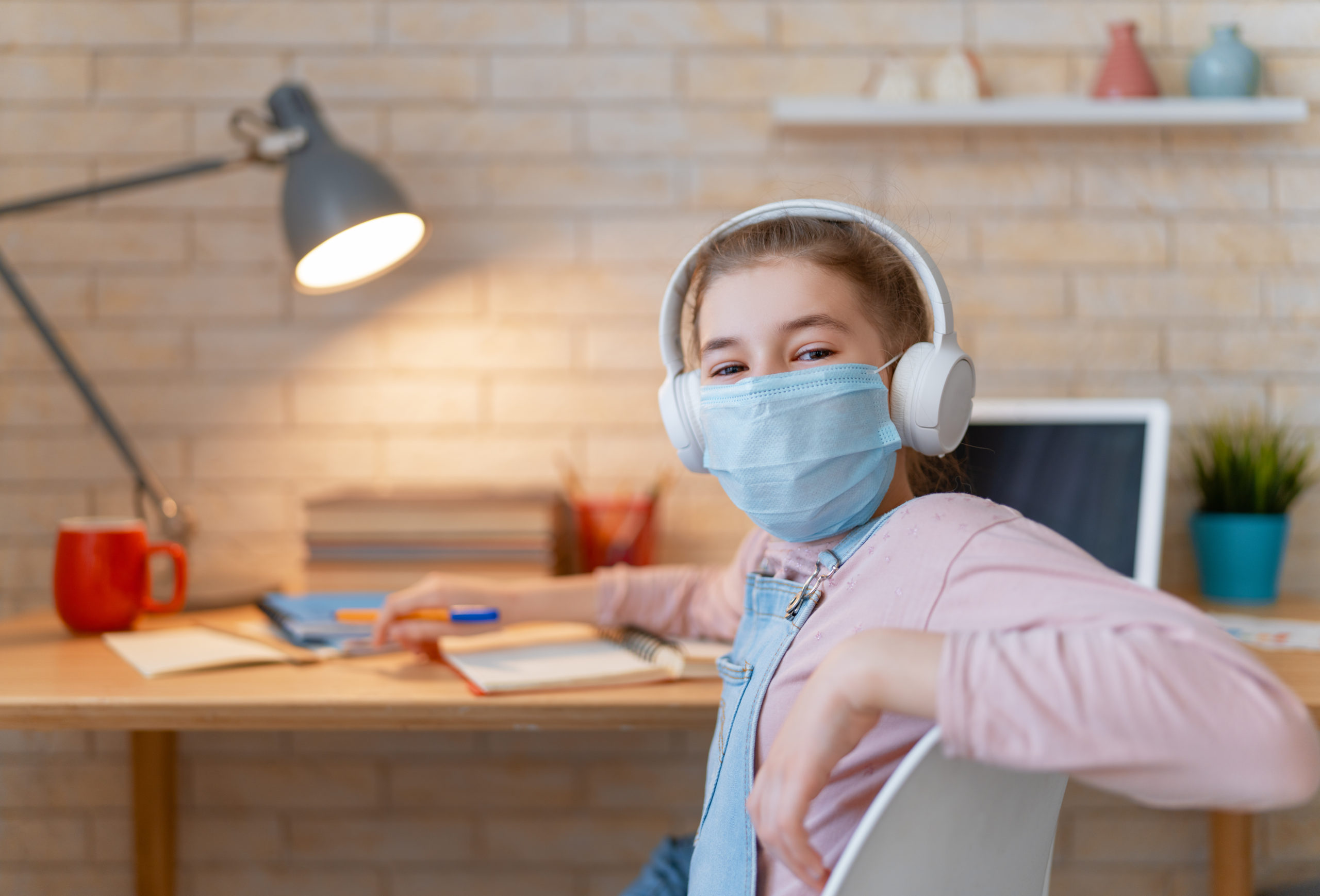 image vedette d'une fille portant un masque facial et utilisant un ordinateur