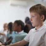 Schoolboy using computer in classroom at primary school
