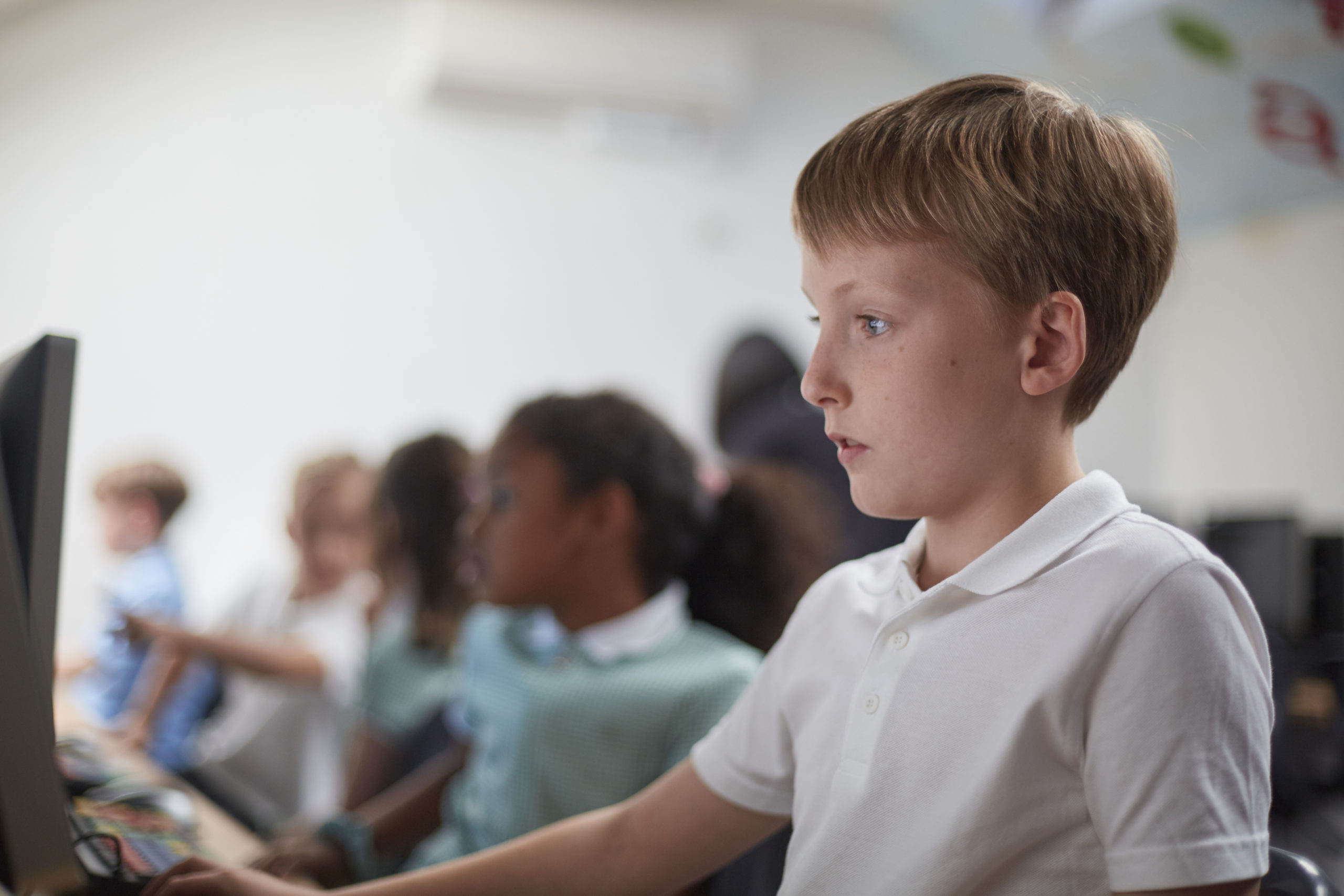 Schoolboy using computer in classroom at primary school