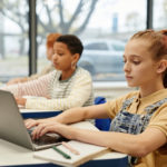 Beitragsbild von Kindern, die im Unterricht einen Laptop benutzen, um die digitale Kompetenz zu fördern