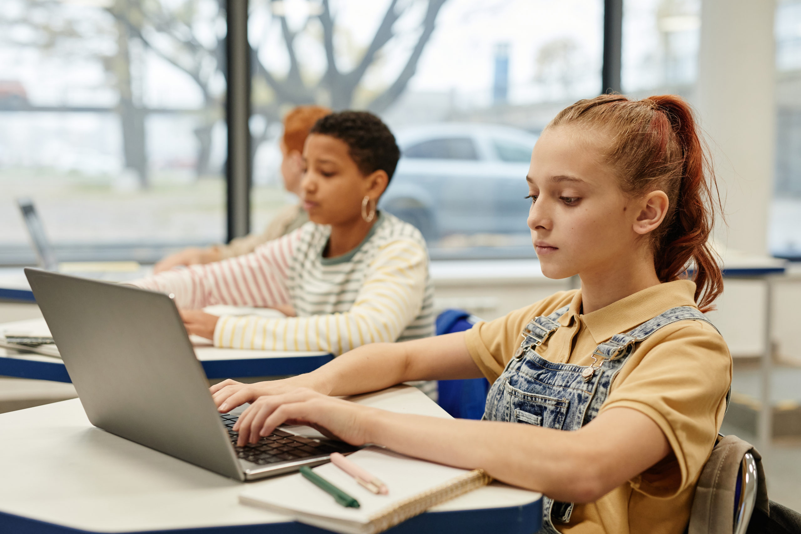 Beitragsbild von Kindern, die im Unterricht einen Laptop benutzen, um die digitale Kompetenz zu fördern