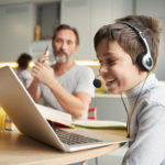 Imagen destacada de un niño utilizando un ordenador y auriculares para evaluar el ELL