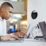 3 étudiants assis à un bureau devant un ordinateur portable