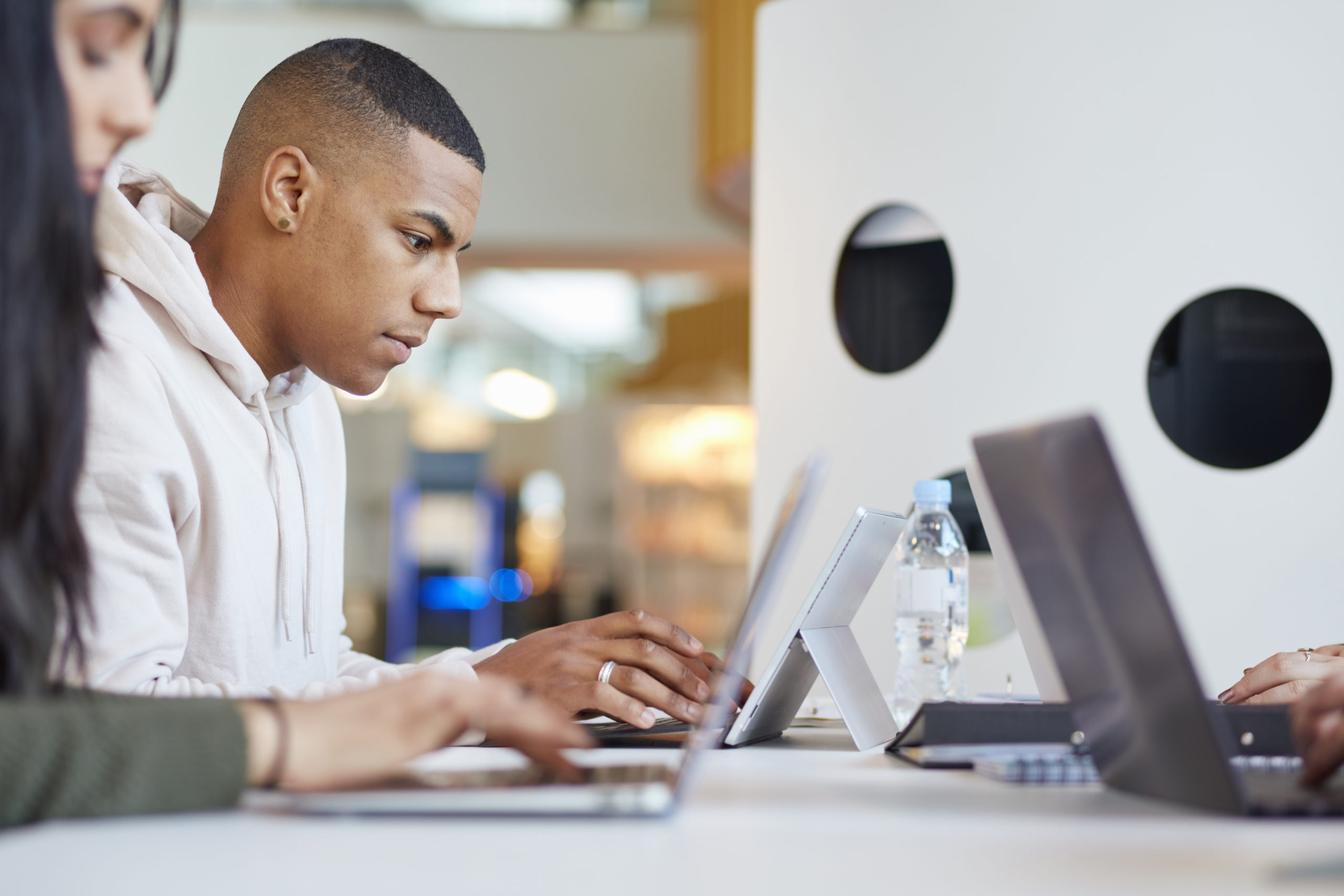 3 Schüler sitzen an Laptops an einem Schreibtisch