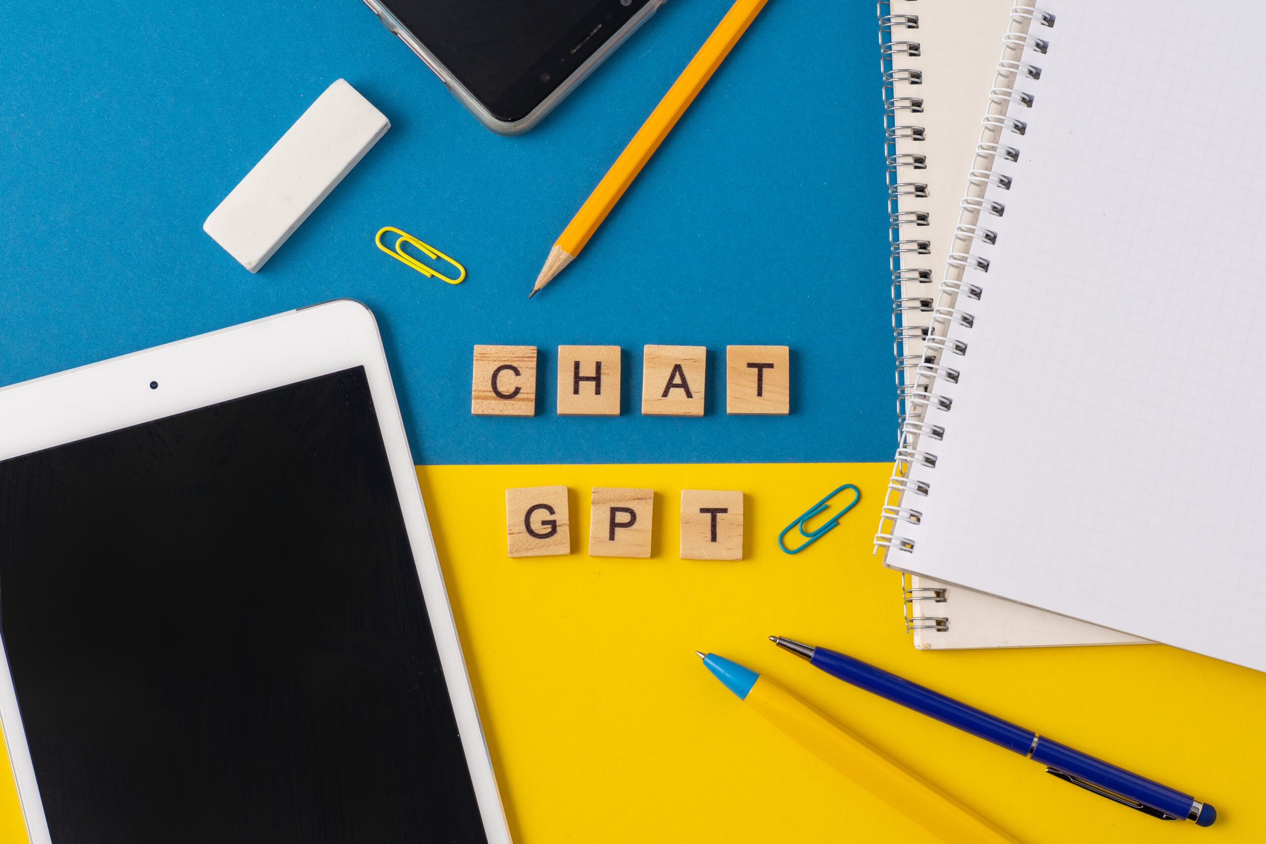 birds eye view of a tablet and pens with tiles spelling out Chat GPT.