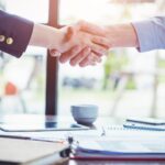 Close up of view of a handshake between two business people wearing suits.