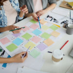 Eine Gruppe von drei Personen sitzt an einem Schreibtisch und plant einen Produktplan für die Prüftechnik.