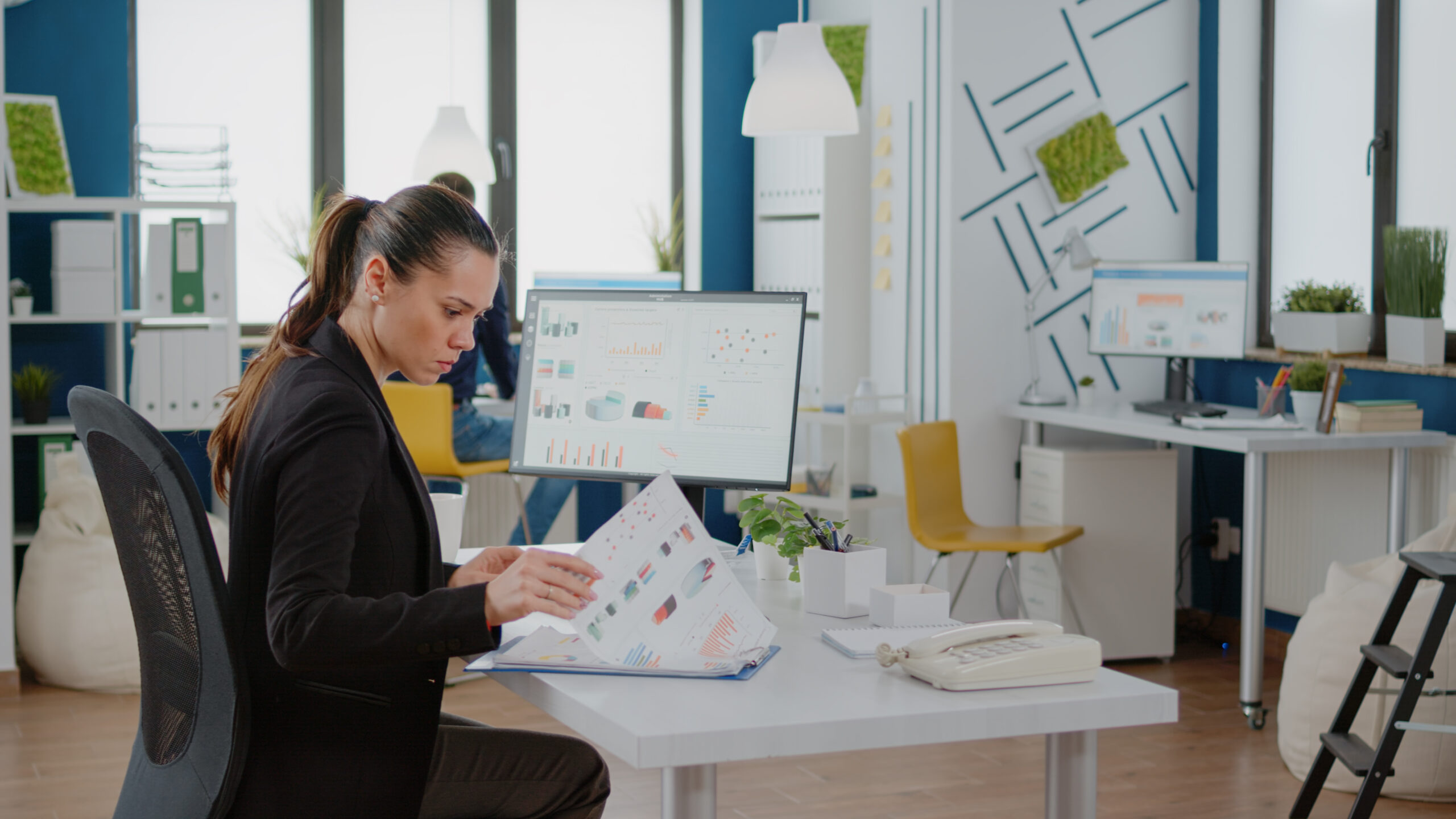 Female educator sitting in an office reviewing data reports measuring student performance on an assessment as learning task.