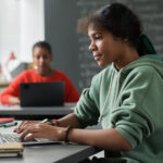 School girl in class using laptop for social emotional learning / SEL assessment.