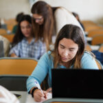 Young students utilizing diagnostic assessment tools in the classroom sitting at a desk with a computer.