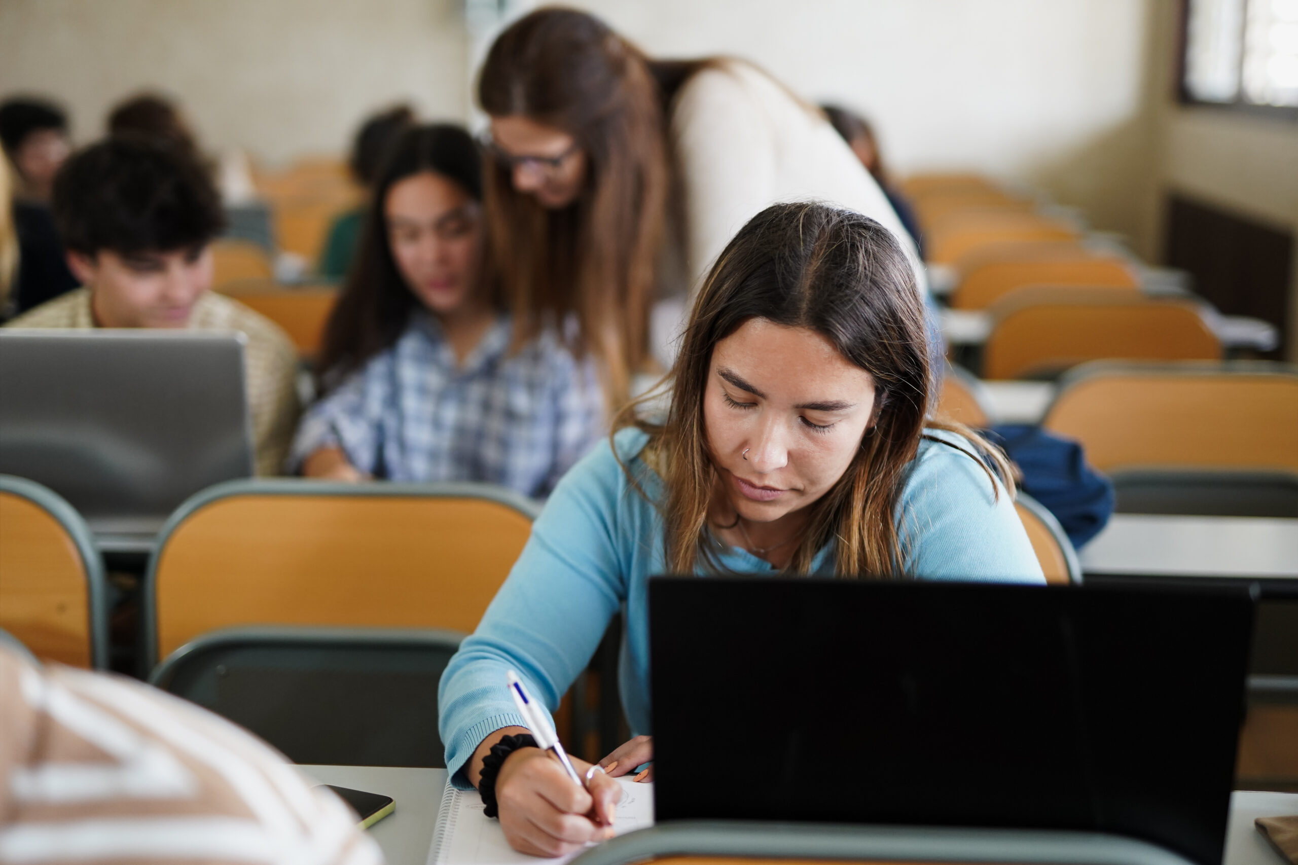 Junge Schüler, die im Klassenzimmer an einem Schreibtisch mit einem Computer sitzen und diagnostische Beurteilungsinstrumente verwenden.