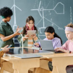 Grupo de alumnos utilizando IA en el aula para aprender nuevas tecnologías con el profesor durante una lección en el aula