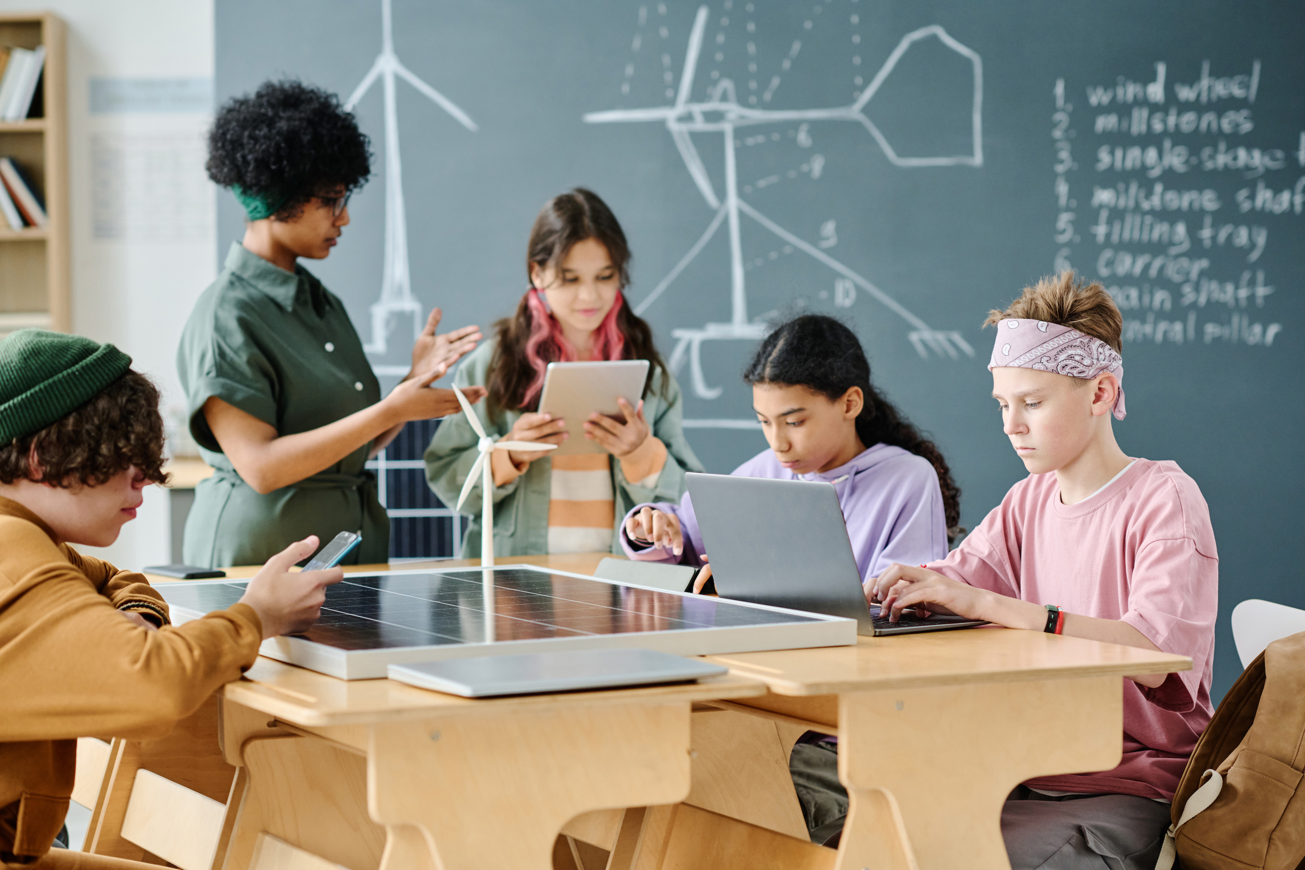 Schülergruppe, die KI im Klassenzimmer einsetzt, um neue Technologien zu erlernen, mit Lehrer während des Unterrichts im Klassenzimmer