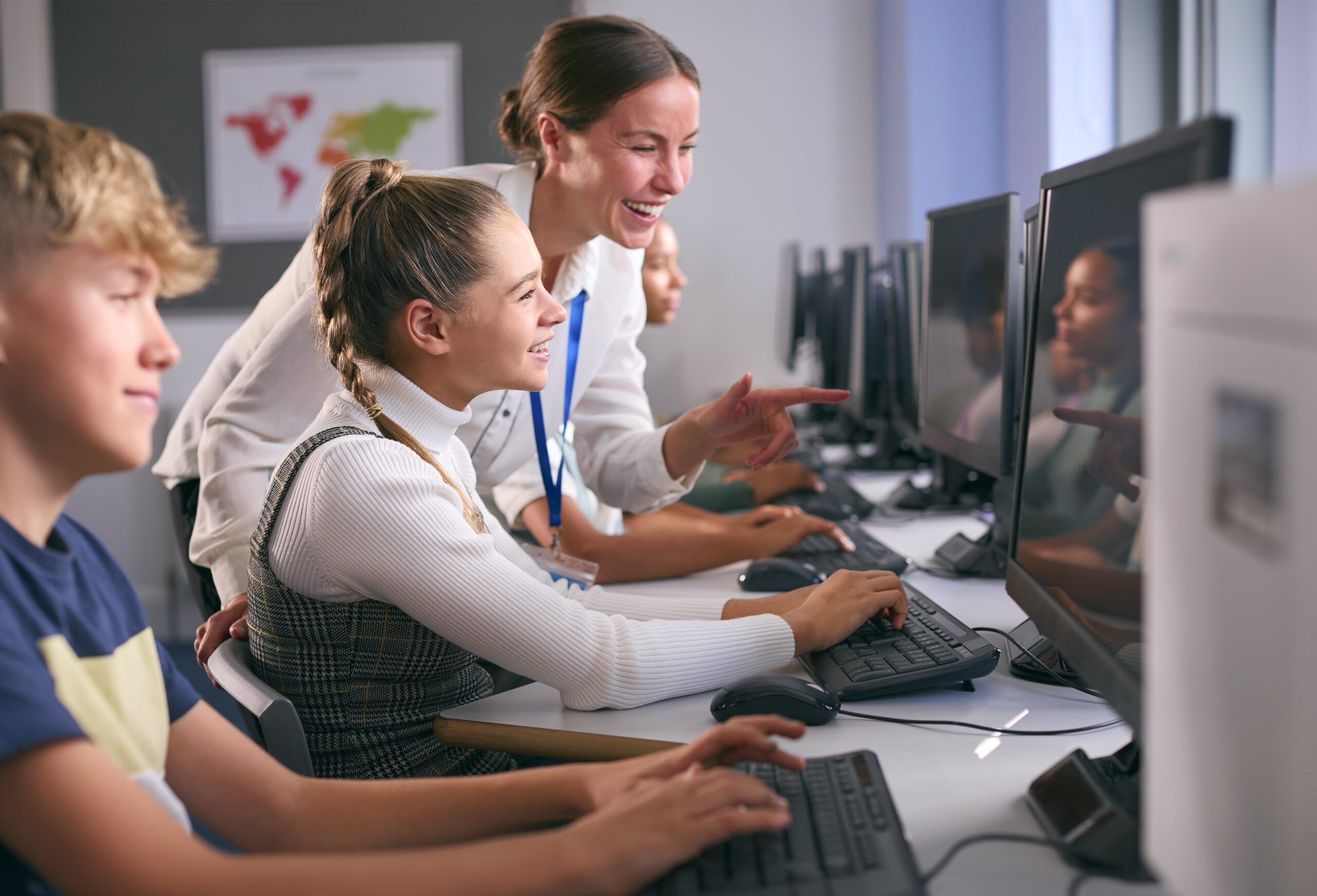 Gruppe von Sekundarschülern an Computern im IT-Unterricht mit einer Lehrerin, die das Konzept des adaptiven Lernens demonstriert