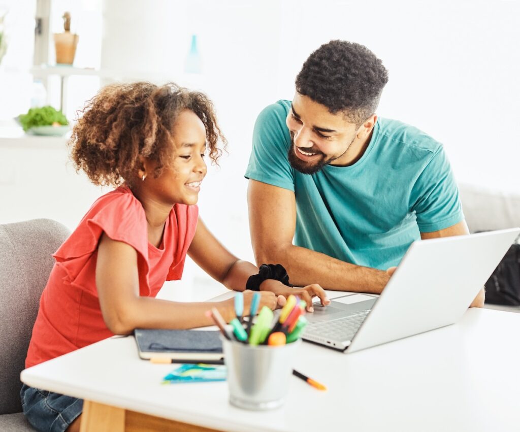 father and daughter having fun doing homework with laptop at home
