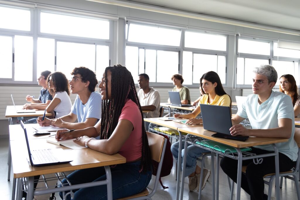 Multiethnische Universitätsstudenten hören dem Lehrer zu und machen sich Notizen im Klassenzimmer