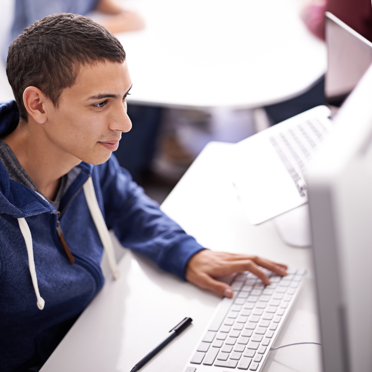 Teenage male student sitting in front of a computer typing on a keyboard, showing the concept of how to study for a test.