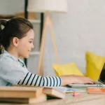 imagen destacada de una niña utilizando un ordenador con los datos de los alumnos protegidos