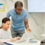 Featured image of teacher engaging with student in the classroom using computer-based formative assessment tools