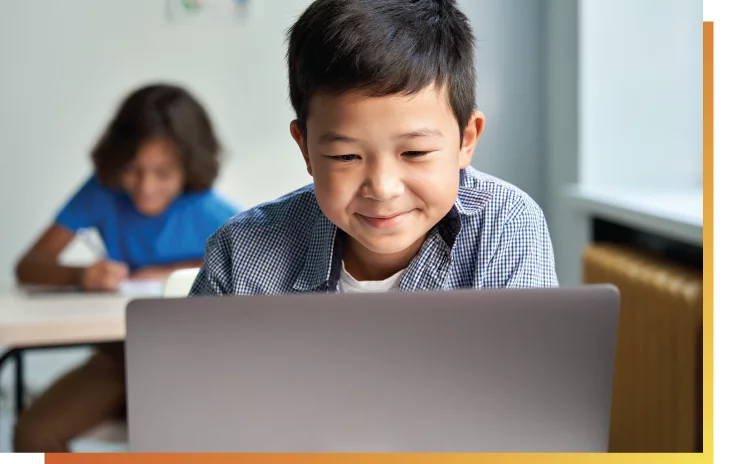 social1-01 smiling young boy sitting in front of laptop looking down