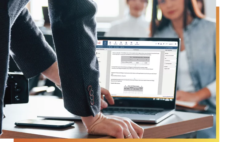 Teacher leaning over laptop with students in the background