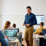 Computer science teacher and high school students having a class in the classroom overcoming the challenges of online learning.