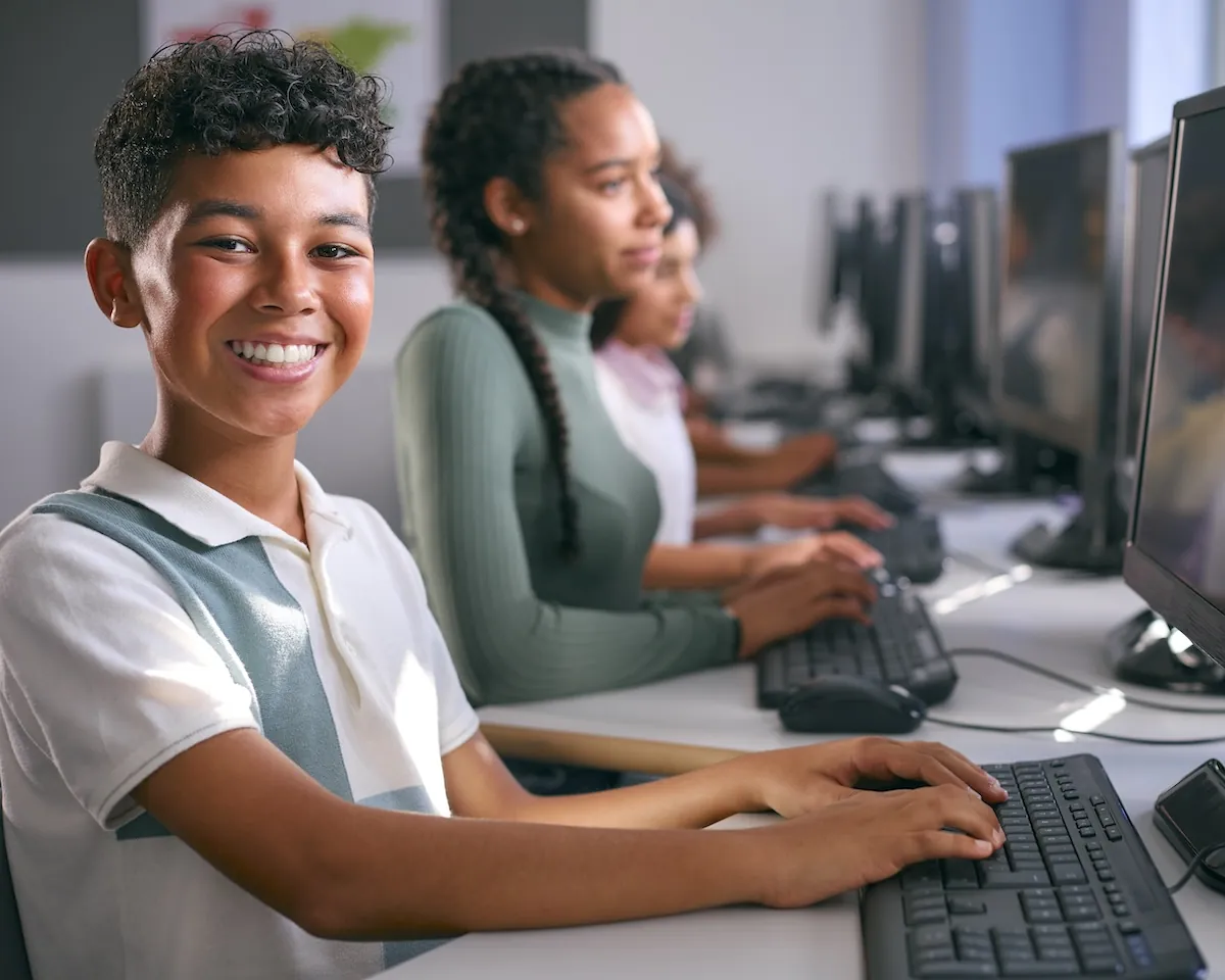 Kids sitting at computers in classroom highlighting the benefits of computer based testing and computer-based tests.