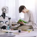 Male student sitting on desk reading a book with a robot teacher standing next to him demonstrating the concept of AI in schools.