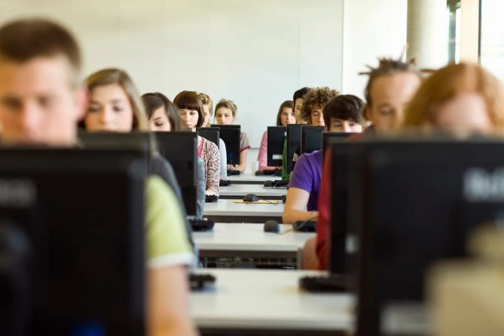 Salle d'étudiants assis dans un laboratoire d'informatique, chaque étudiant regardant l'écran de son bureau, démontrant une application pratique d'outils de gestion d'examens open source dans un cadre éducatif.