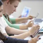 教室でデジタルタブレットを使う2人のティーンエイジャーのクローズアップ